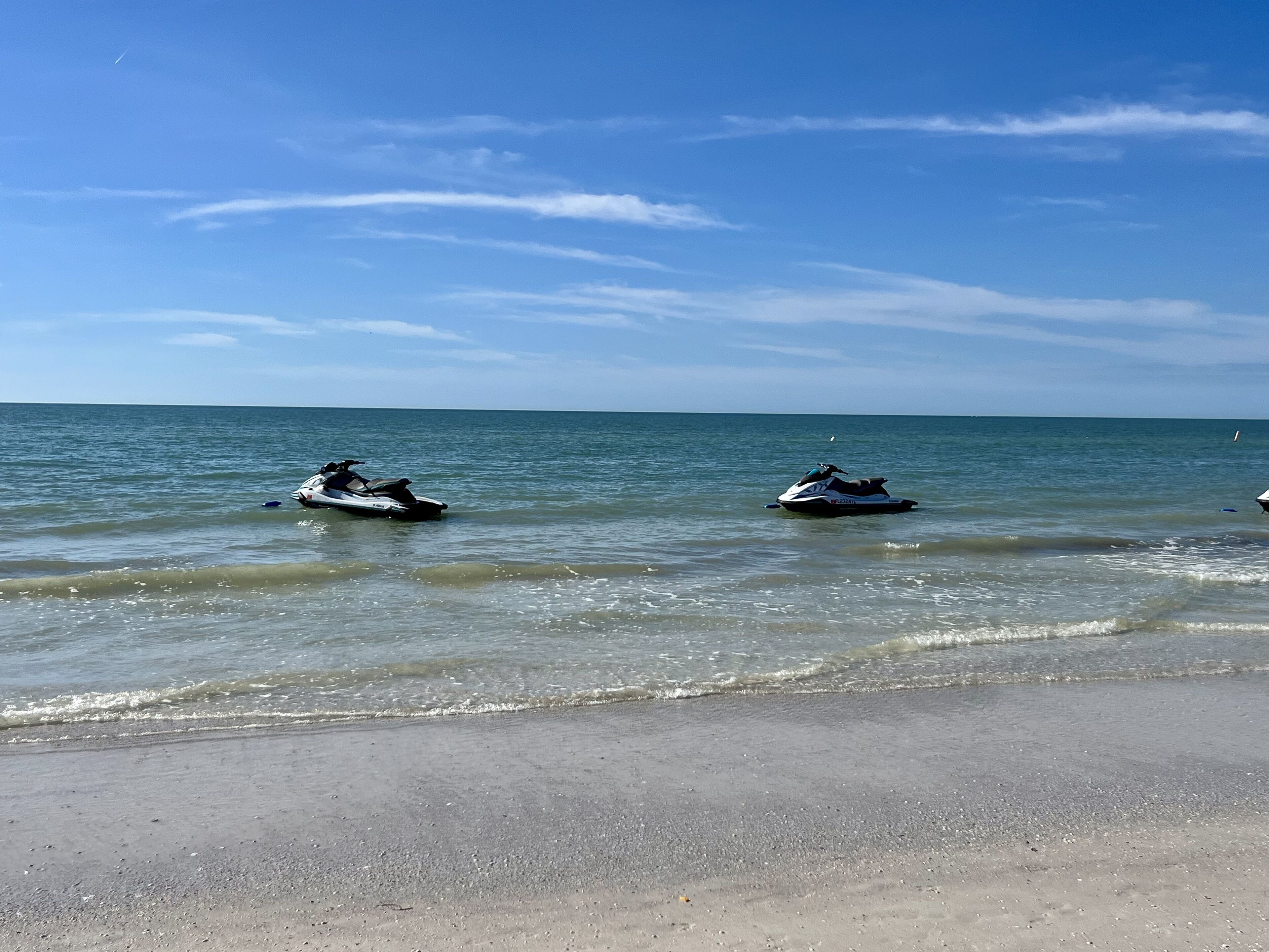 Una spiaggia con due jet ski sull'acqua e una riva sabbiosa.