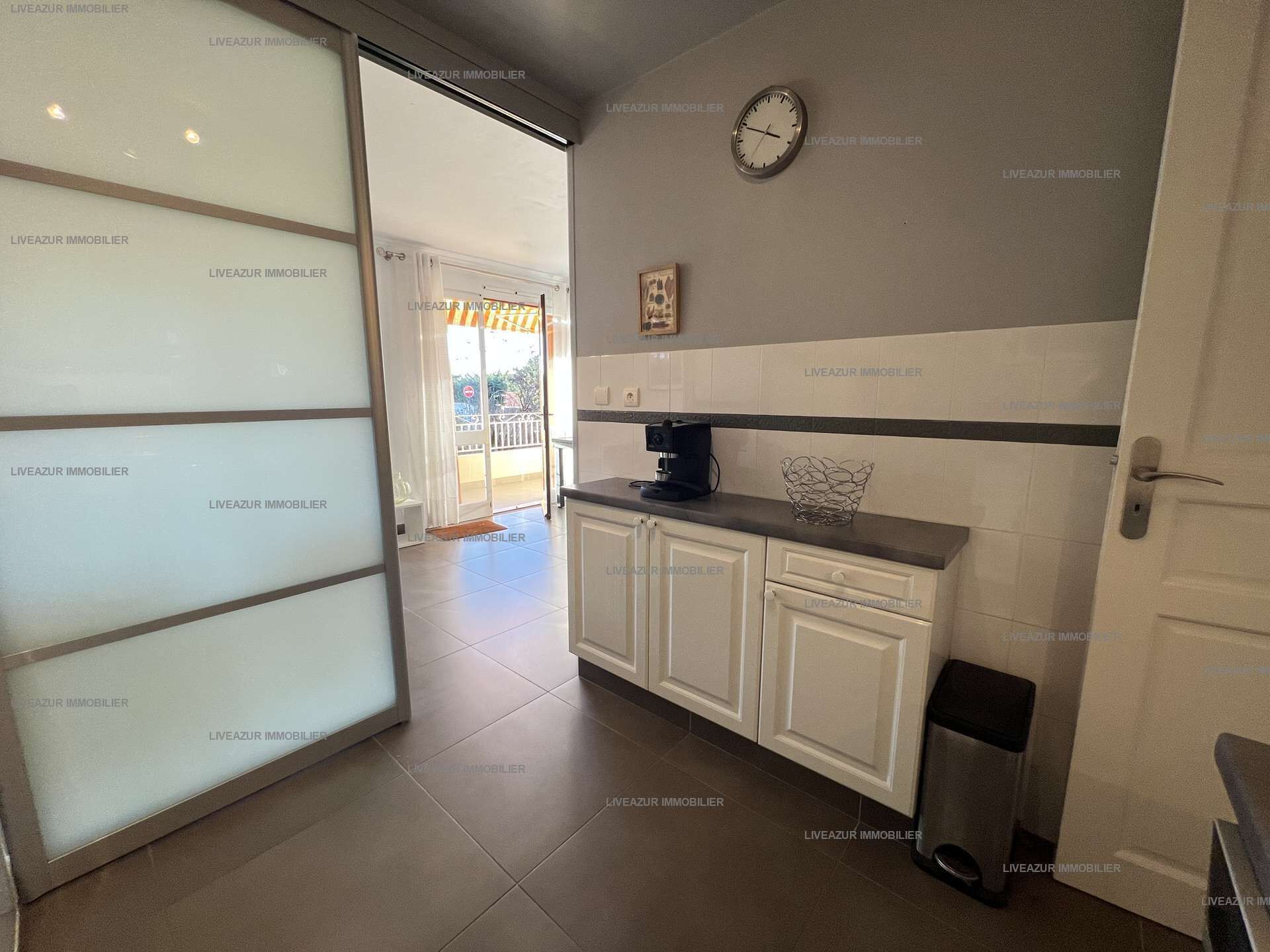 A kitchen with white cabinets, a coffee machine, and a clock on the wall.