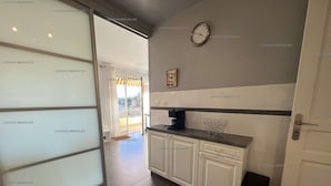 Une cuisine avec des meubles blancs, une machine à café et une horloge au mur.