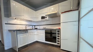 Une cuisine moderne avec des meubles blancs, un four à micro-ondes encastré et un réfrigérateur.