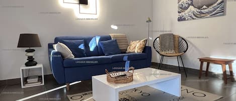A modern living room with a blue sofa, a coffee table, and a wall-mounted light fixture.