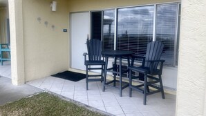 A patio with a table and chairs, a door, and a window with blinds.