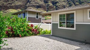 A single-story house with a gravel driveway and a small garden with red flowers. - Mountain View|Single Lvl Home|Beach 5 Min|Free Prk (Waianae)