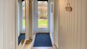 A hallway with a door leading to a garden, a welcome sign, and three baskets on a doormat. - 3 bedroom awesome home in Hejls (Hejls)