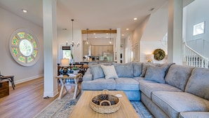 A spacious living room with a large sectional sofa, a wooden coffee table, and a dining area with a chandelier. - Private Heated Pool - 3 Min Walk to Beach - Golf Cart - Beach Chair Service (Destin)
