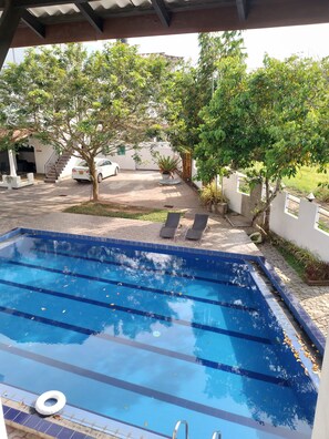 A swimming pool with clear blue water, surrounded by a tiled deck and a few lounge chairs. - Shiromi Hotel Katunayaka (Seeduwa - Katunayake)