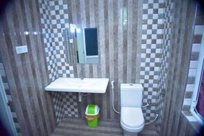 A compact bathroom with a checkered tile wall, a white sink, a mirror, and a toilet. - Shiromi Hotel Katunayaka (Seeduwa - Katunayake)