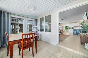 Un comedor con mesa y sillas, una cocina con armarios y electrodomésticos, y vista al exterior.