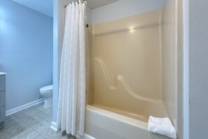 Un baño con bañera, inodoro y cortina de ducha.