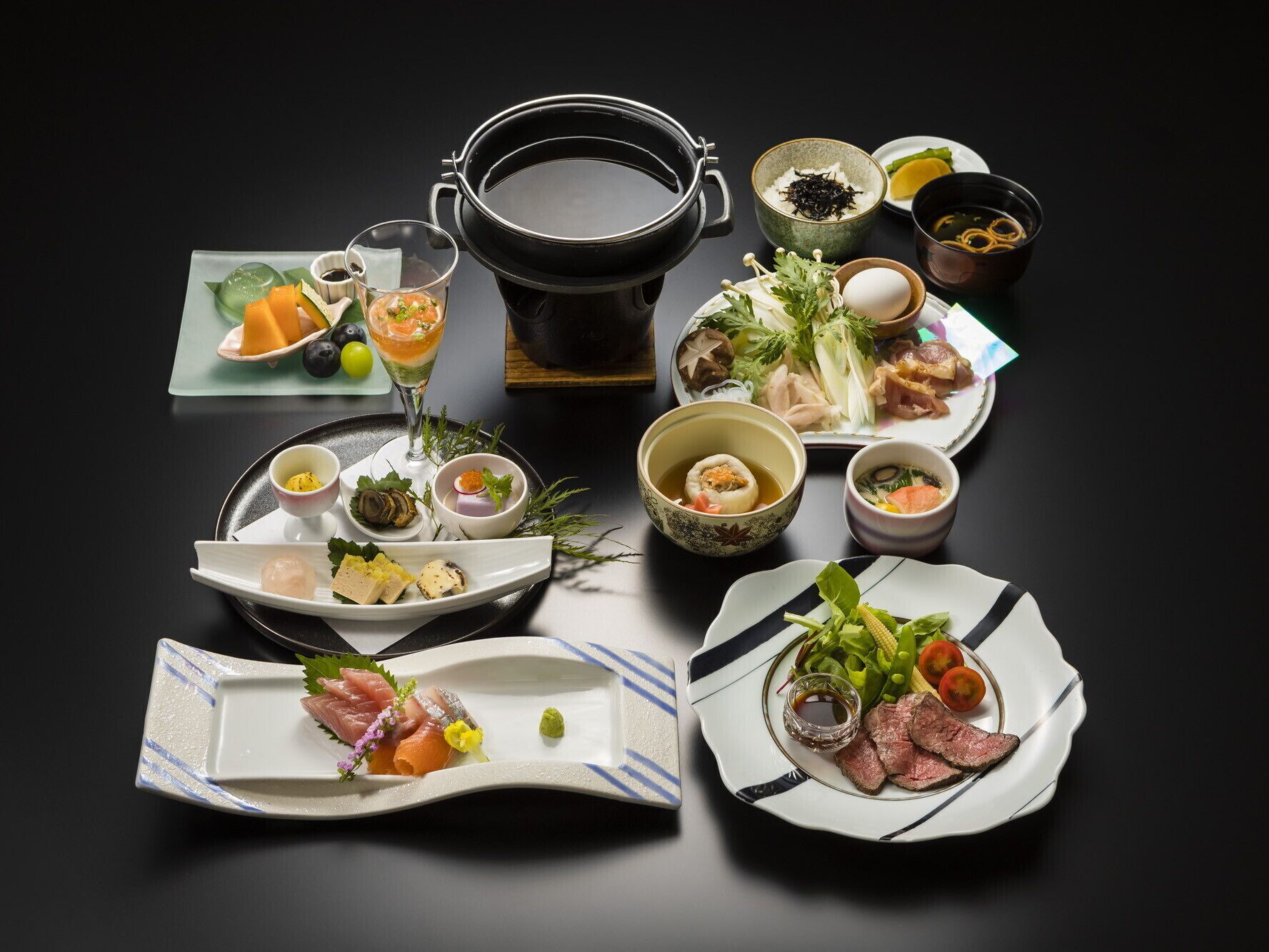 A variety of Japanese dishes including sushi, sashimi, and a hot pot setup.