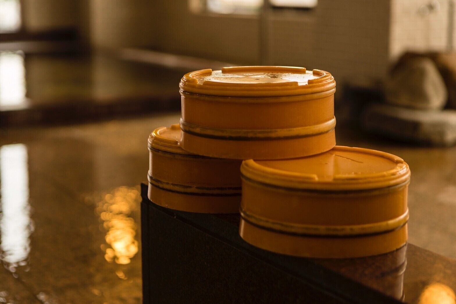 Three stacked containers with lids on a reflective surface.