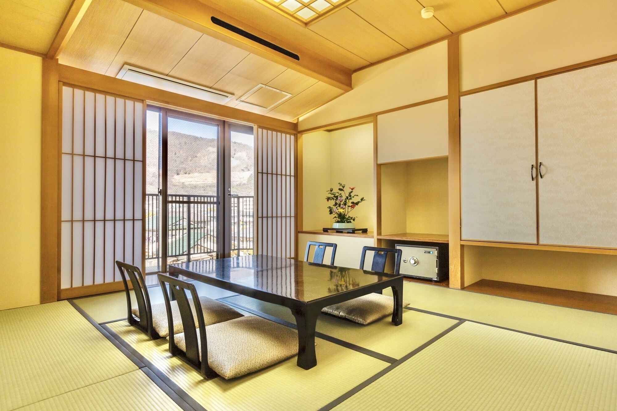 Een traditionele Japanse kamer met tatami vloeren, een lage tafel met stoelen, schuifdeuren en een kast.