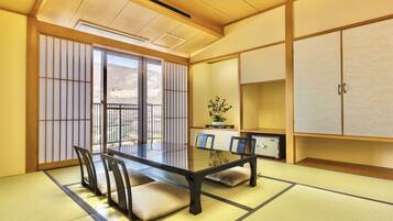 Een traditionele Japanse kamer met tatami vloeren, een lage tafel met stoelen, schuifdeuren en een kast.