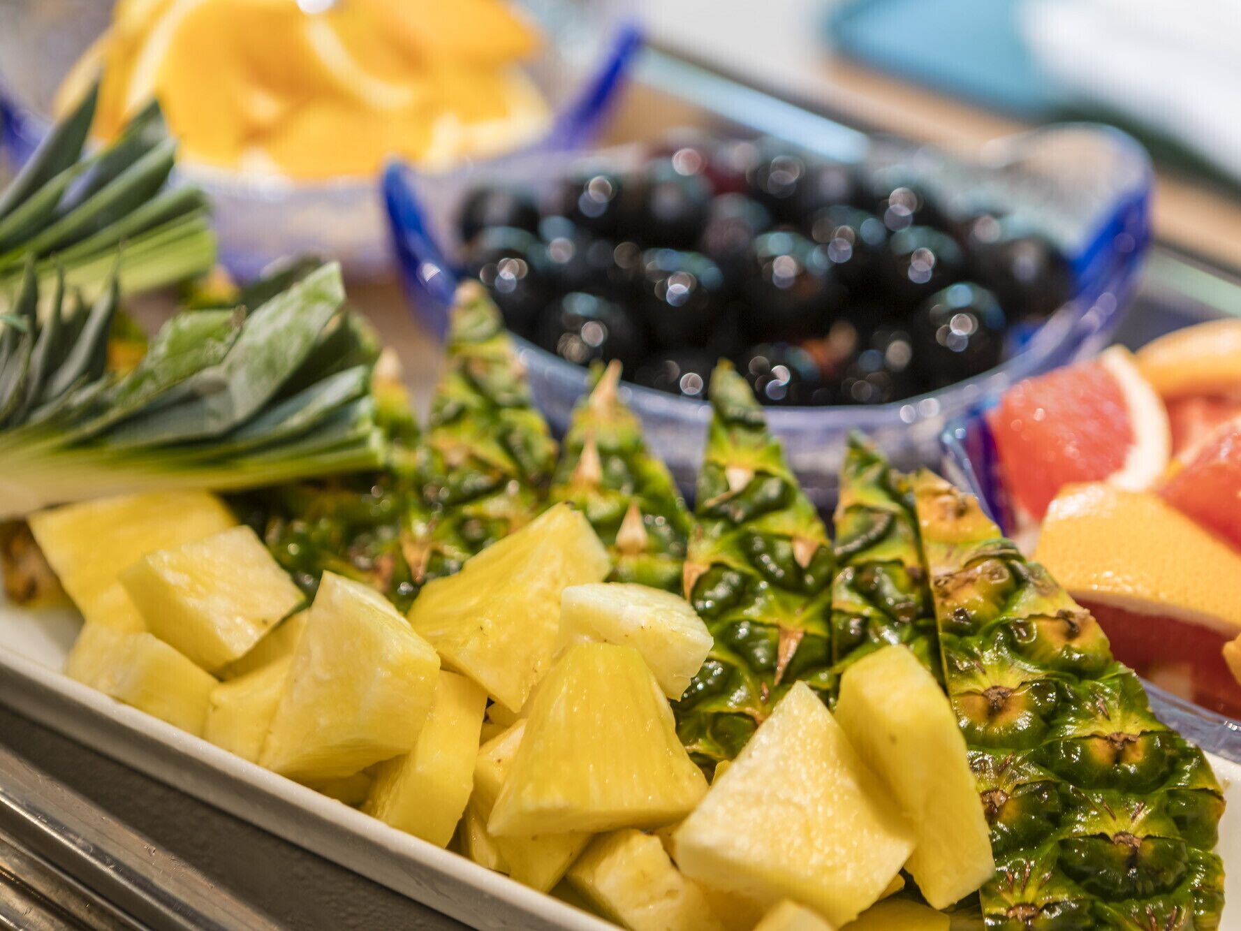 Un buffet proposant des morceaux d’ananas, des légumes verts et un bol d’olives noires.