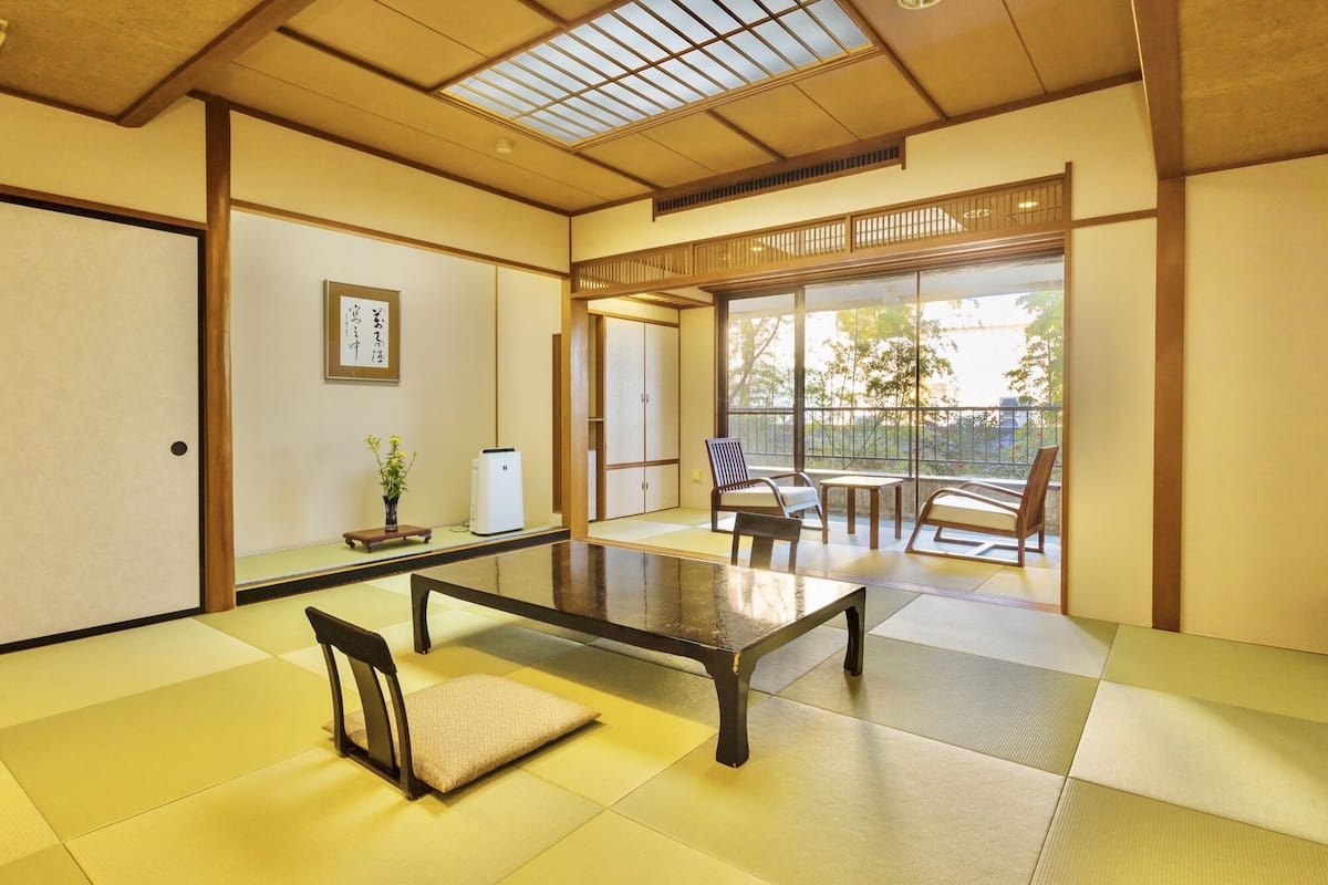 A traditional Japanese room with tatami flooring, a low table, and sliding doors.