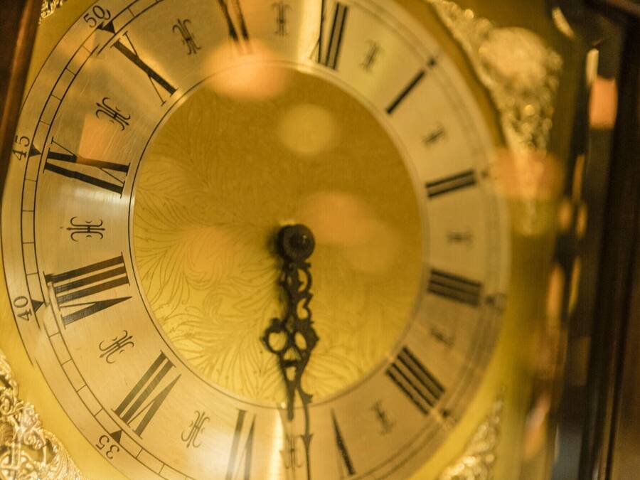 Primer plano de una esfera de reloj con números romanos y diseños intrincados.