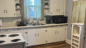 A kitchen with white cabinets, a stove, a microwave, and a sink. - Hidden Oasis of West Columbia (West Columbia)