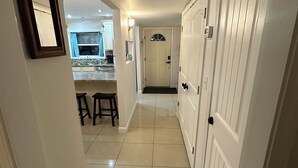 Un couloir qui s’ouvre sur un espace cuisine, avec une table et des chaises de salle à manger visibles au fond.
