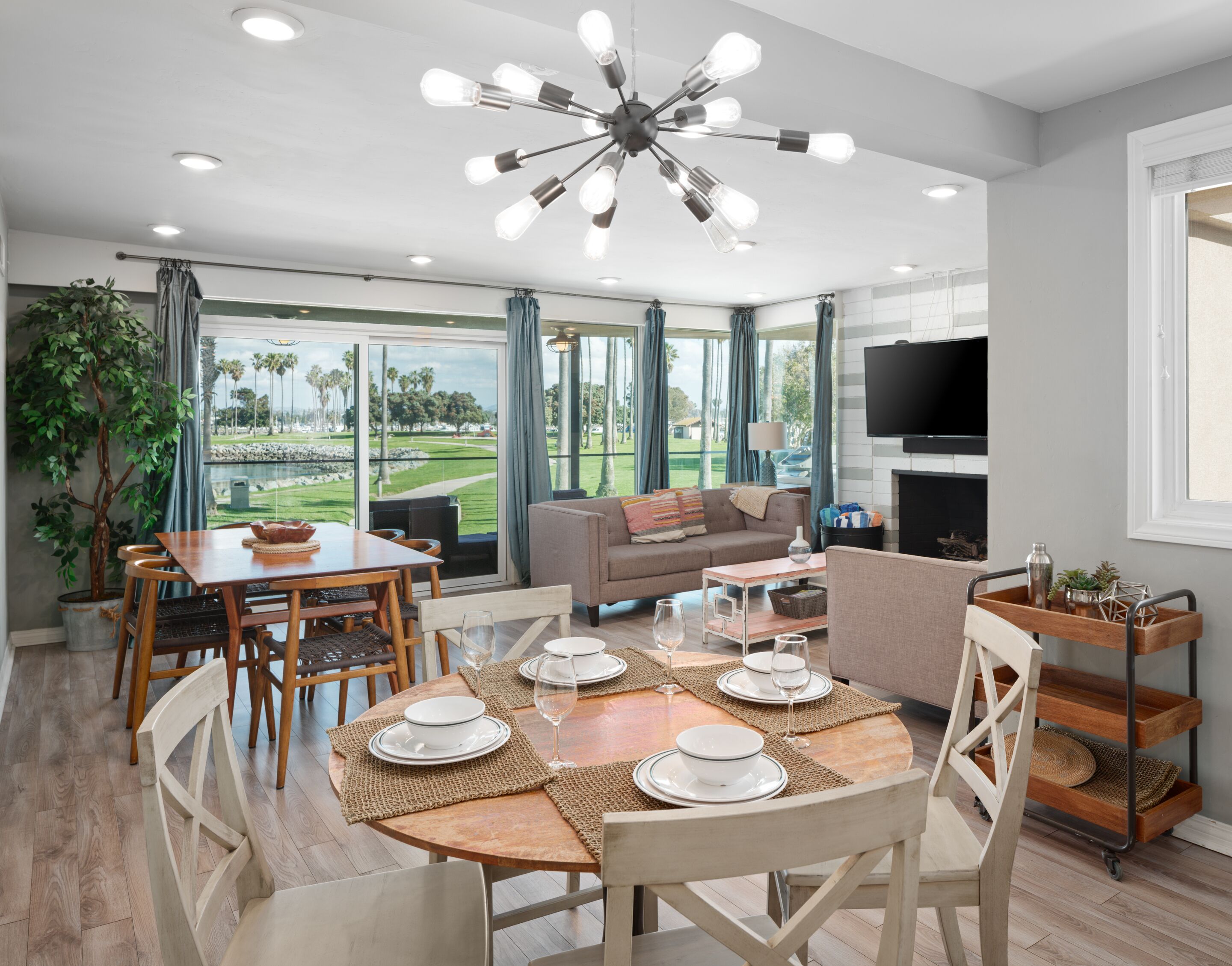 Un vaste espace de vie comprenant une table à manger pour quatre personnes, un canapé, un téléviseur et une vue sur un terrain de golf.