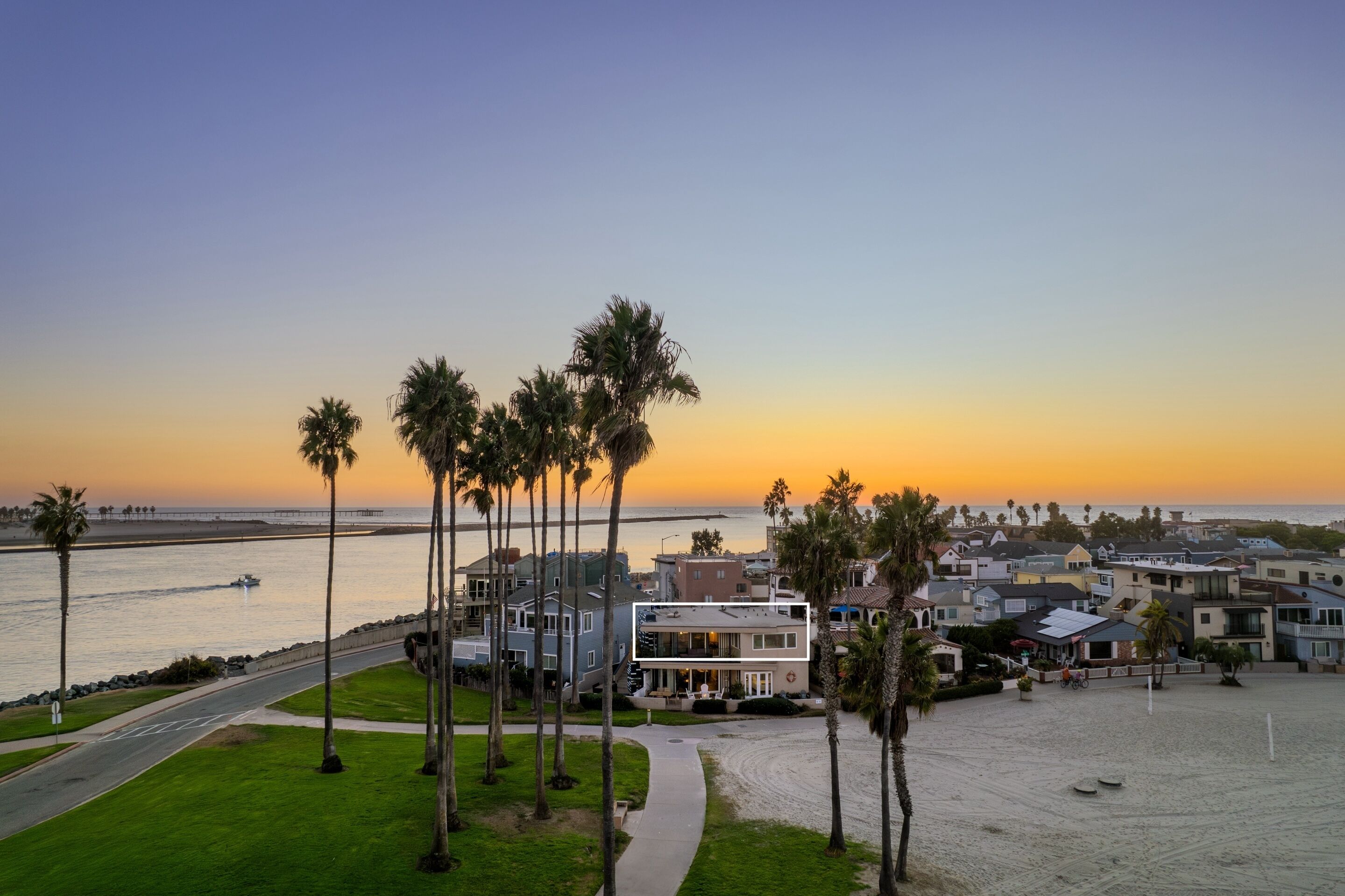 A coastal residential area with houses, palm trees, and a beach.