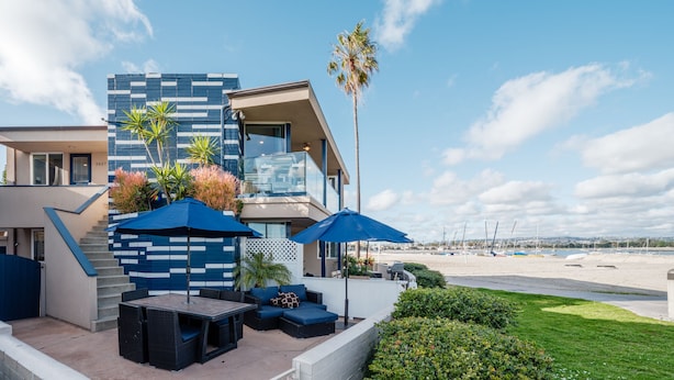 A modern building with a balcony, outdoor seating, and a view of the beach. - Bayfront | Ultimate Family Fun | AC | Parking (San Diego)