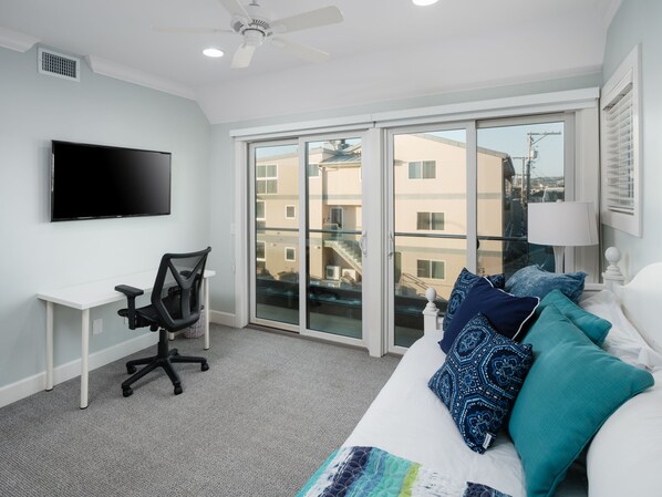 A modern bedroom with a large bed, a desk, and a TV. - Oceanfront Penthouse w/ Unlimited Views & AC (San Diego)