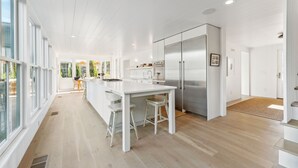 Eine moderne Küche mit weißen Schränken, Edelstahlgeräten und einer großen Kochinsel mit Barhocker.