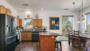 A modern kitchen with wooden cabinets, a black refrigerator, and a dining area with a wooden table and chairs. - Stylish and comfortable home in a prime location. Close to golf, hiking & biking (Sedona)