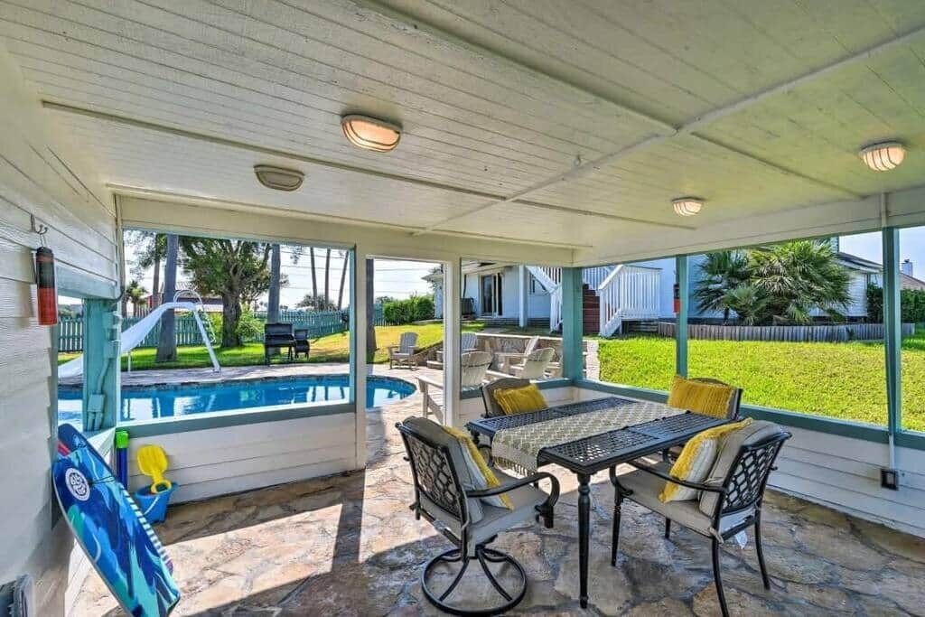 Un patio techado con piscina, mobiliario exterior y vista al jardín trasero.