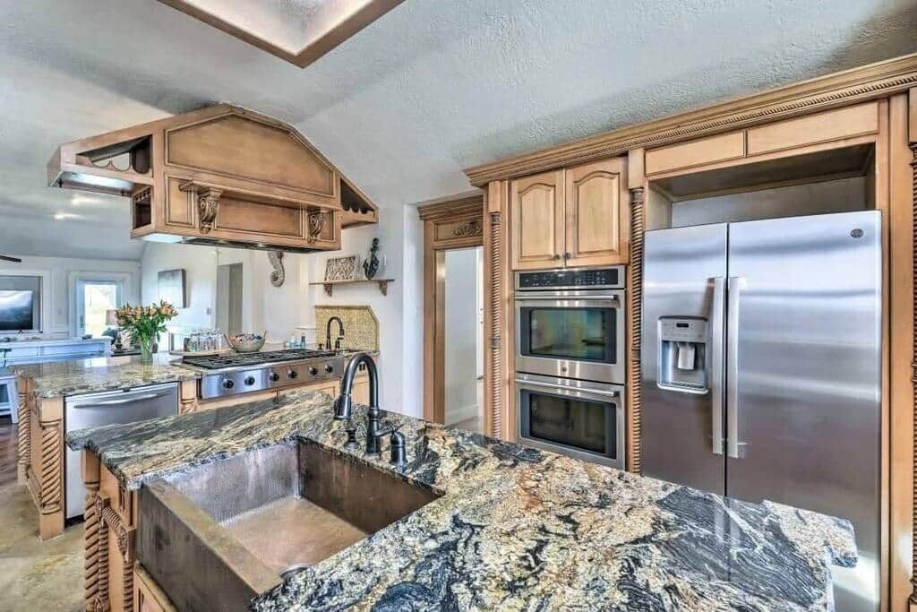 A kitchen with granite countertops, stainless steel appliances, wooden cabinetry, and a built-in oven.