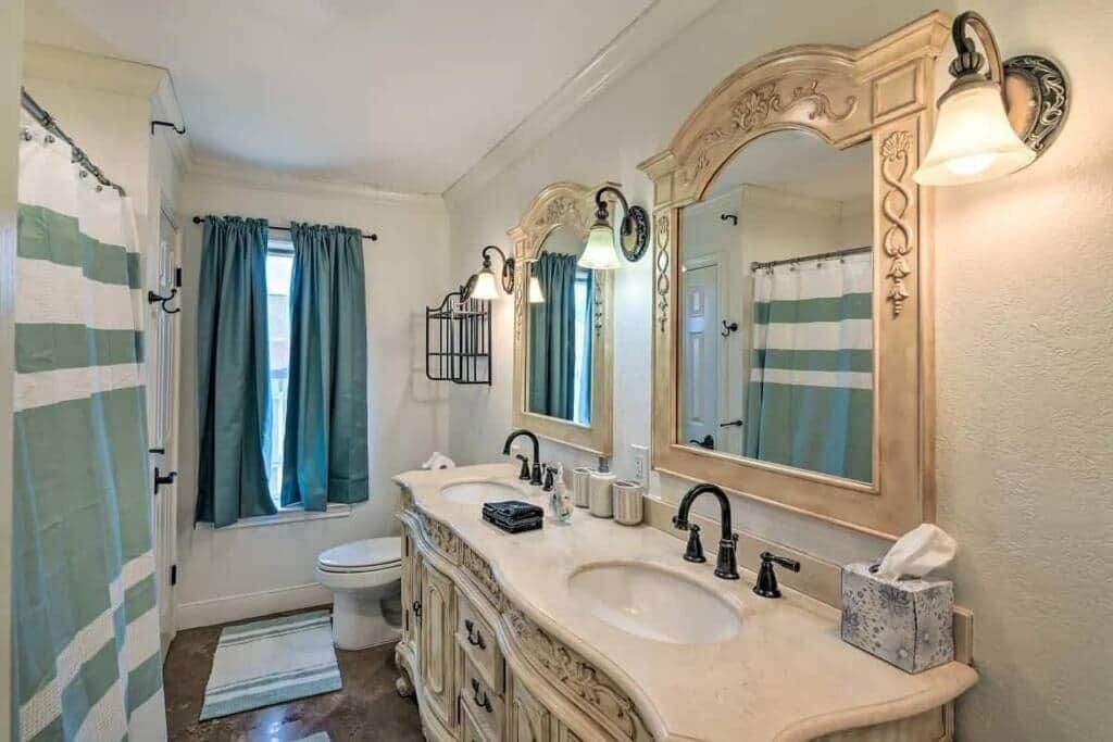 Une salle de bain avec un meuble-lavabo à deux vasques, un grand miroir et un rideau de douche.