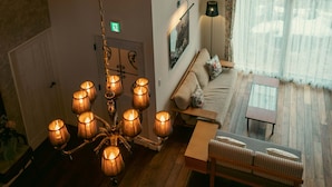Amplia habitación con techo de madera, un candelabro, un sofá, una mesa de centro y un gran ventanal con cortinas.