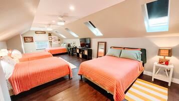 A bedroom with two beds, a desk, a TV, and a skylight.