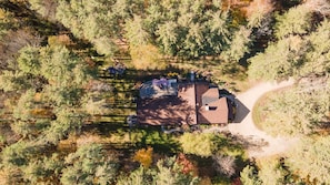 Vista aérea de una casa rodeada de bosque denso, con un camino despejado hacia la entrada.