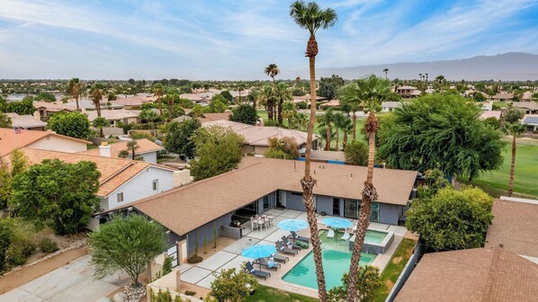 A residential area with houses, a swimming pool, and palm trees.