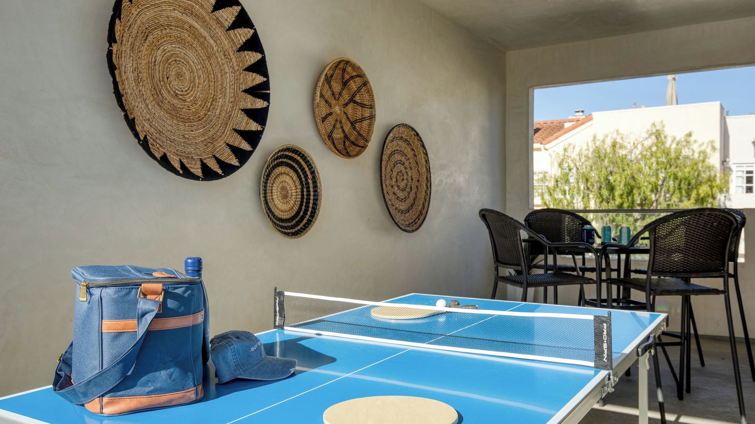 A ping pong table with a blue surface, a blue bag, and a cap on the table.