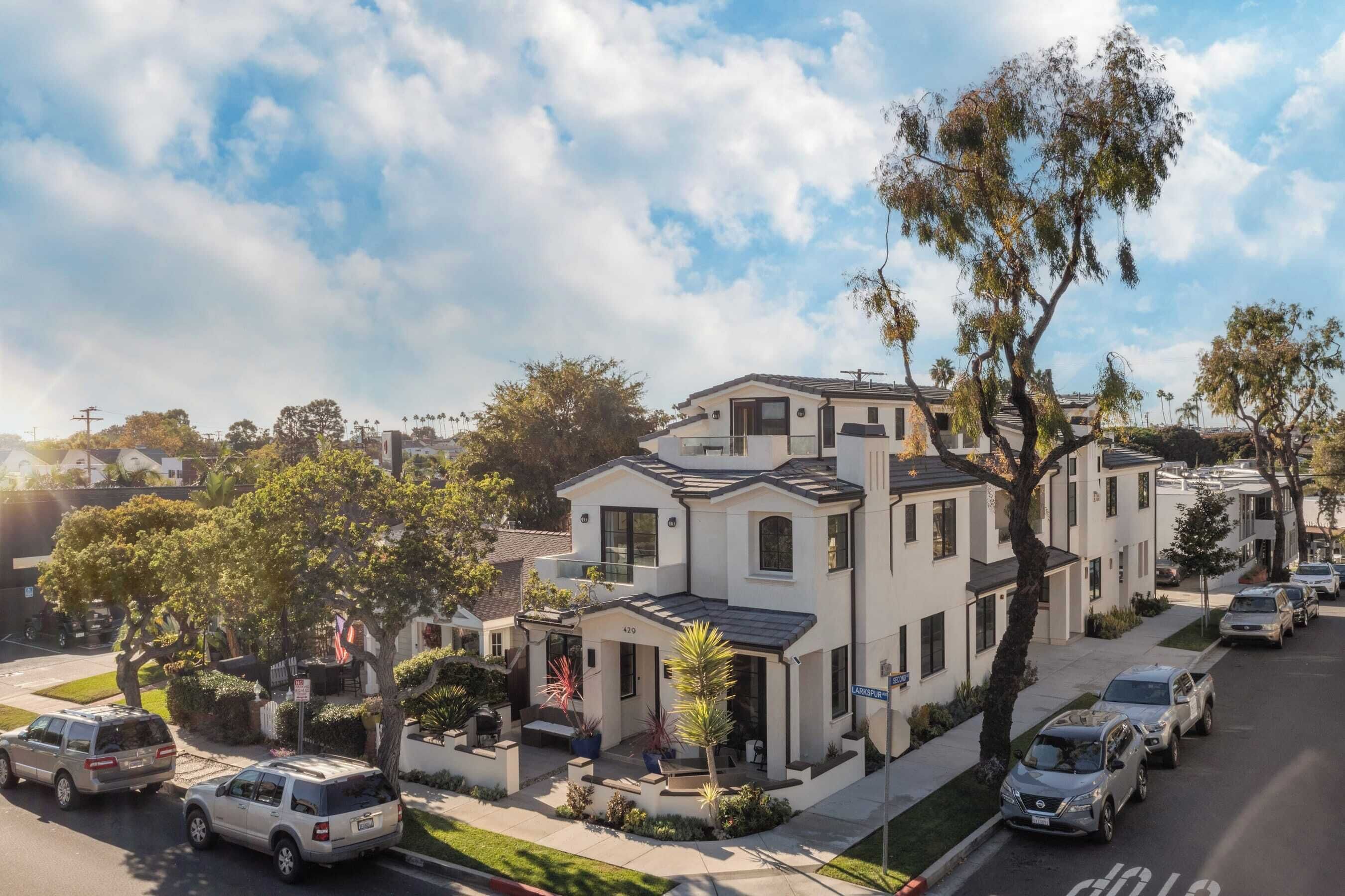 A modern two-story house with a front porch, a driveway, and parked cars.