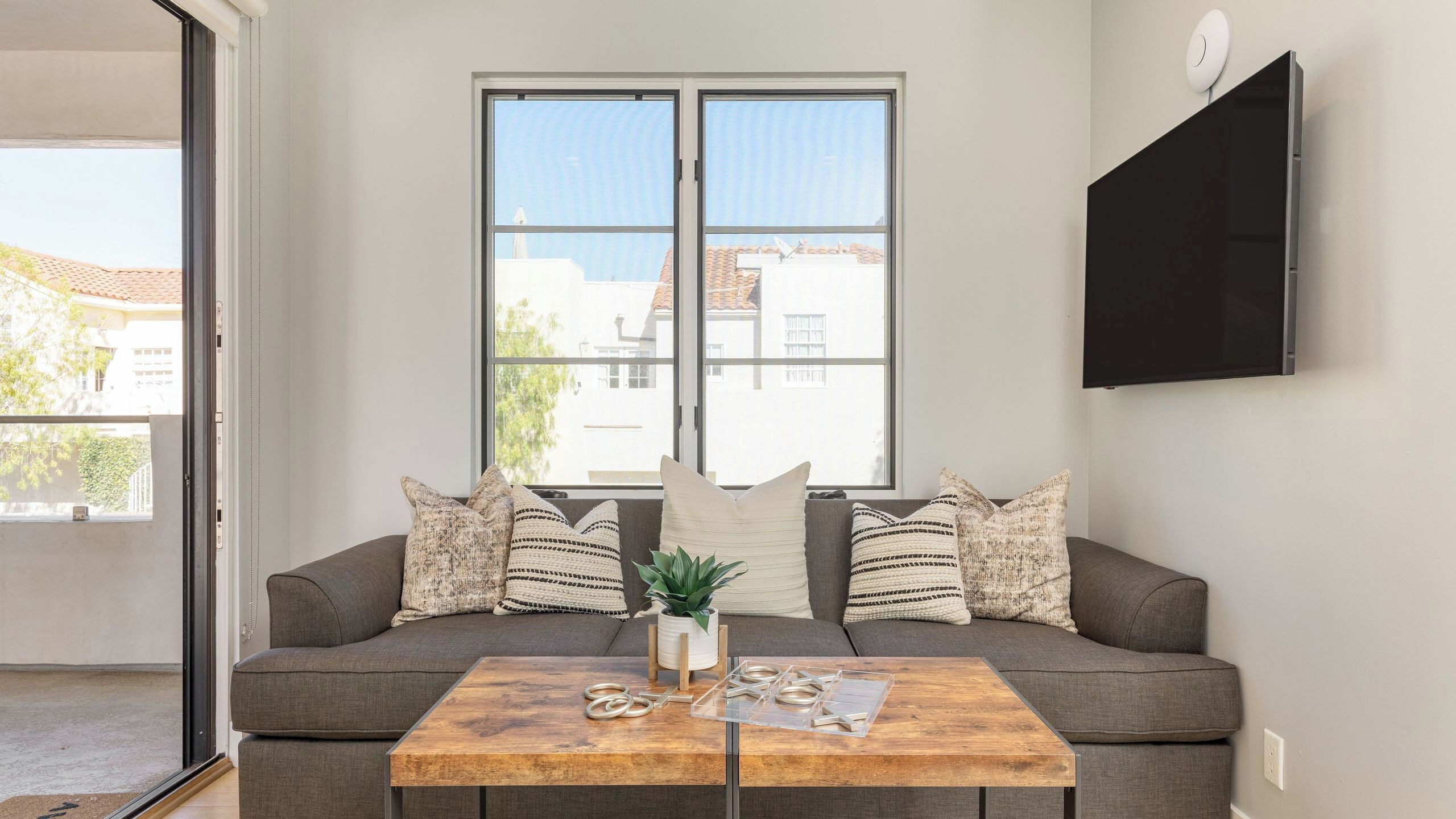 A living room with a sofa, a coffee table, and a TV mounted on the wall.