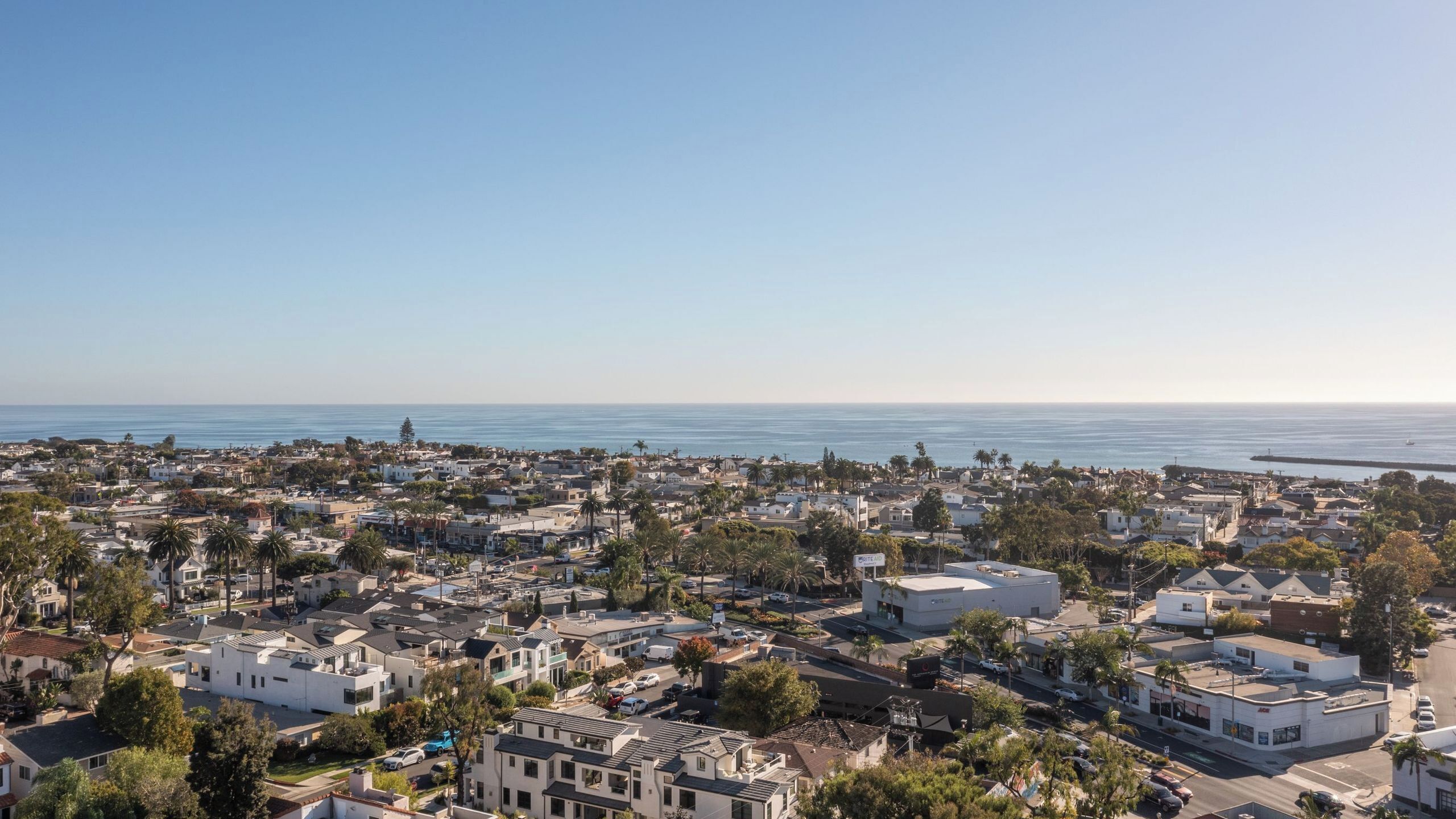 A coastal town with residential buildings, a marina, and a clear view of the ocean.
