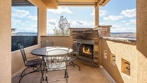 Un patio con chimenea de piedra, una mesa redonda y sillas.