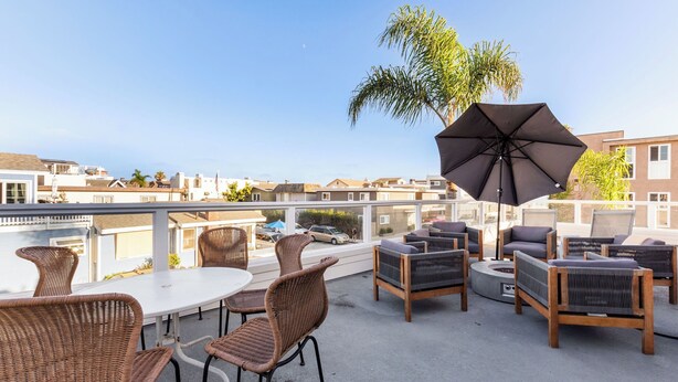 Une terrasse sur le toit, aménagée avec des meubles en osier, un grand parasol et offrant une vue sur le quartier.