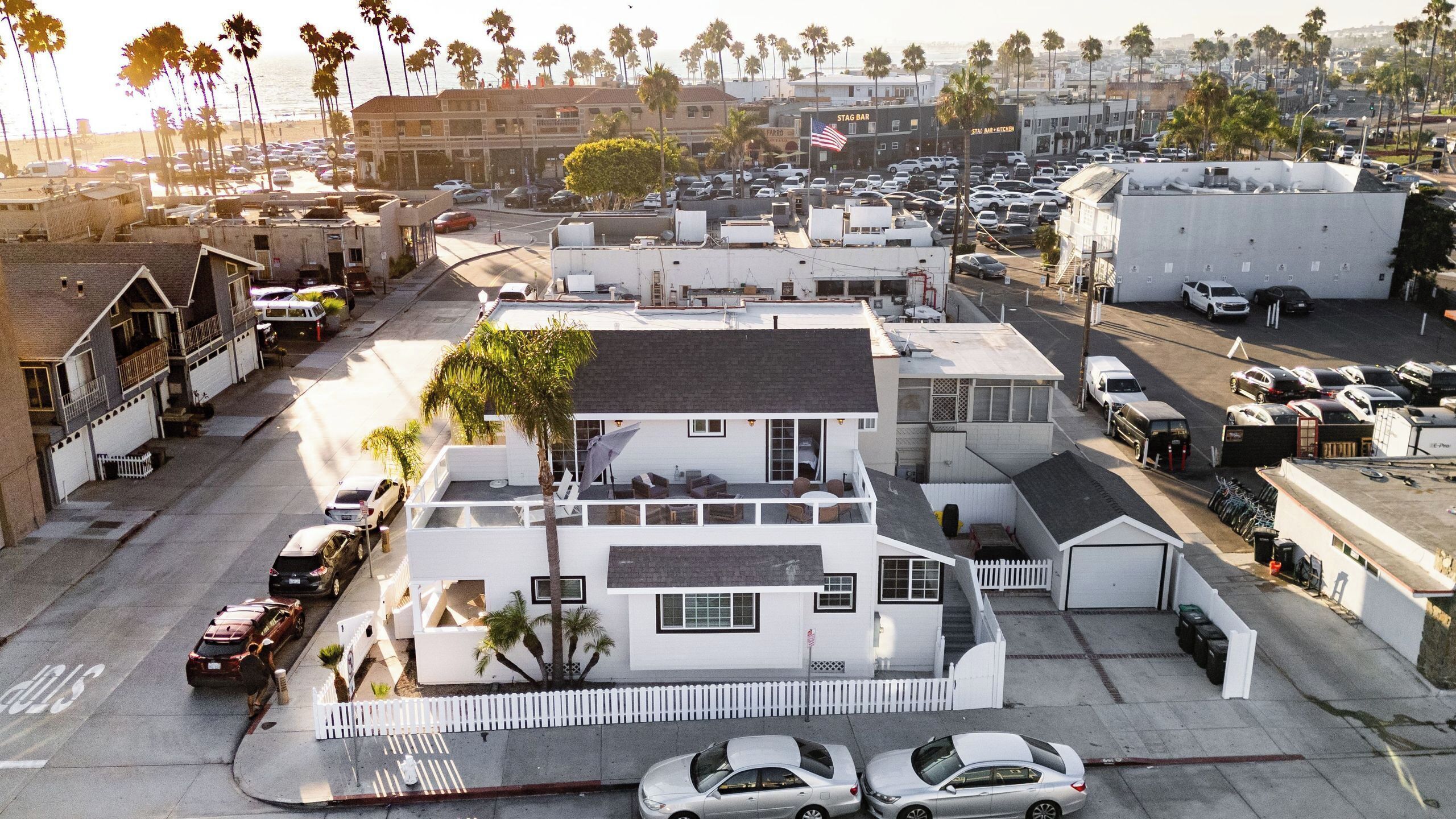A multi-story residential building with a garage, a balcony, and a parking lot with cars.