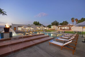 Un espace piscine avec des chaises longues et un foyer.