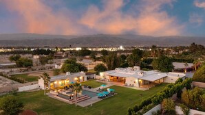 A large, modern house with a spacious backyard, a swimming pool, and a view of distant mountains.