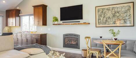 A living room with a fireplace, a television, and a dining area with a table and chairs.