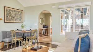 A living room with a grey sofa, a wooden coffee table, and a dining area with a round table and chairs.