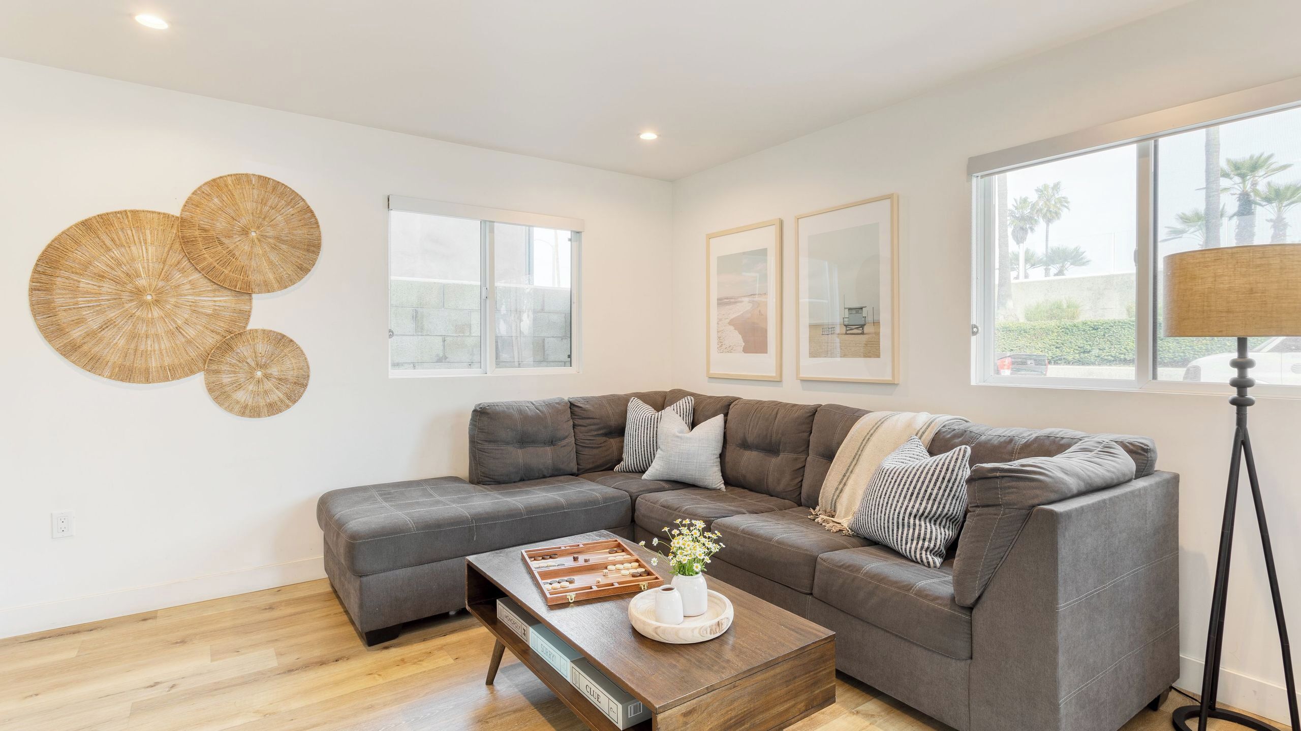 A modern living room with a sectional sofa, a coffee table with a board game, and a floor lamp.
