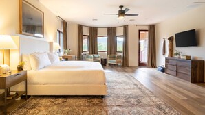 Un'ampia camera d'albergo con un letto grande, una scrivania, una sedia, una televisione e vista sull'esterno.