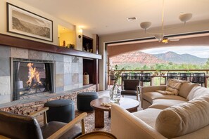 A living room with a stone fireplace, comfortable seating, and a view of red mountains. - Pyramid by Avantstay Luxe Sedona Mansion w/ Views, 7mins to Downtown (Sedona)