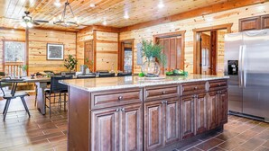 A spacious kitchen with wooden walls, a central island, and a stainless steel refrigerator.